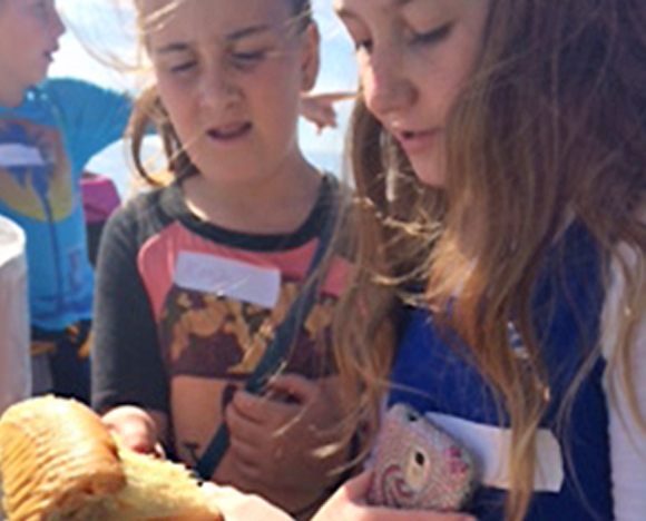 Two young girls observe a piece of coral while participating in the marine science education program.